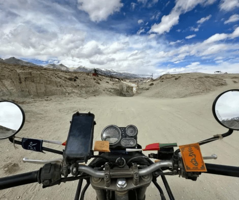 A first-person perspective of a Royal Enfield rider on Mustang’s dusty, high-altitude trails, showcasing the vast, untouched beauty of Nepal’s Himalayan region.