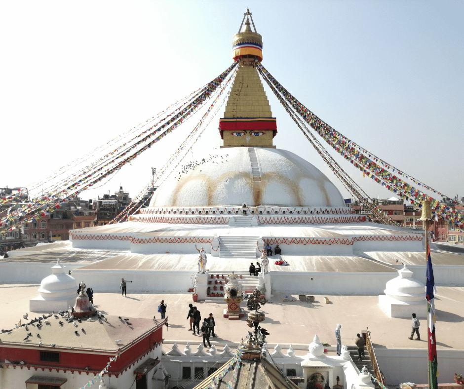 The majestic Boudhanath Stupa in Kathmandu, adorned with prayer flags and surrounded by devotees and travelers seeking spiritual connection.