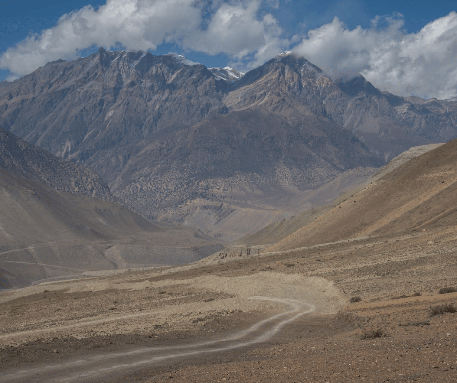  A barren yet mesmerizing view of Mustang’s rugged terrain, featuring winding paths through dramatic mountain valleys.